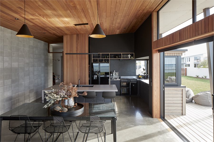 The dining area features an over-the-wall sliding door with large fixed windows above it. Sliding and casement windows let light into the black kitchen.