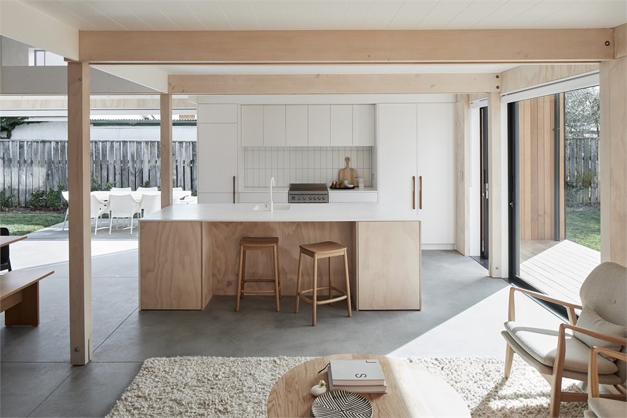 The minimal aesthetic is maintained by a pale Corian benchtop with a waterfall edge. The home's laminated timber posts and beams are by Techlam. Extra-large sliding doors with flush sills offer a seamless transition into the garden.