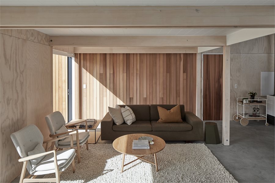 Cedar cladding offers visual warmth outside and in the living area, where a pair of oak Fable armchairs by Citta sit with a sofa by David Shaw that Nikki reupholstered to give it a new lease on life.