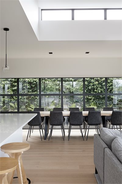 An expansive 21-panel grid of fixed Metro Series windows opens the room onto a green wall