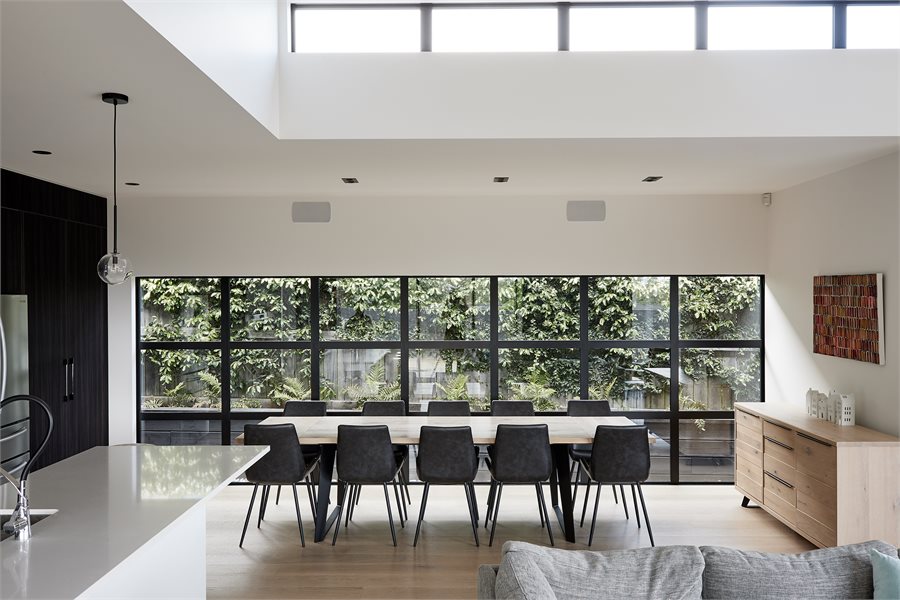 An expansive 21-panel grid of fixed Metro Series windows opens the room onto a green wall